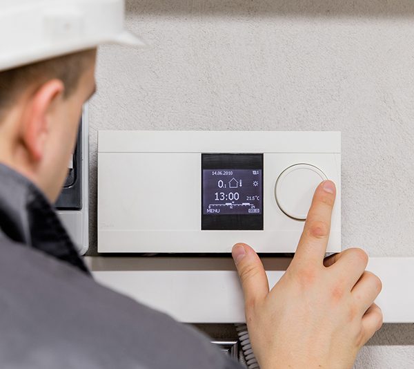 Engineer adjusting thermostat for efficient automated heating sy